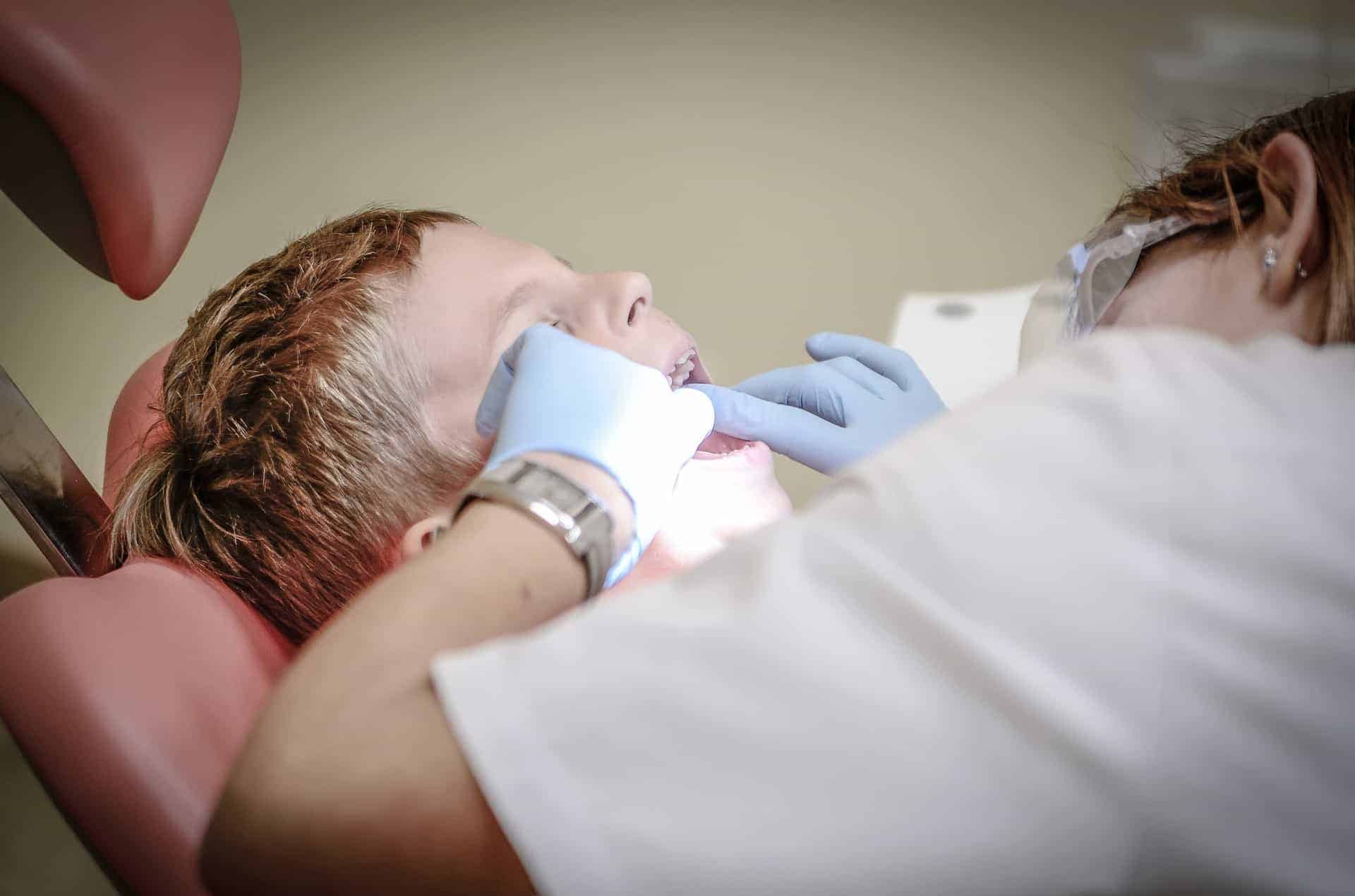 Childrens Dental Health Check Raynes Park - A Young Patient Is Undergoing A Dental Health Check At Beverley Dental In Raynes Park. The Dentist, Wearing Gloves And Protective Eyewear, Carefully Examines The Child's Teeth While The Patient Reclines Comfortably In A Dental Chair. The Setting Is A Modern Dental Clinic, Reflecting The Professional And Caring Approach Of Beverley Dental Towards Children's Oral Health. This Scene Highlights The Clinic's Commitment To Providing Comprehensive Dental Care For Children, Ensuring Their Dental Health Is Monitored And Maintained In A Safe And Supportive Environment.